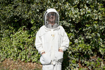 Portrait of beekeeper looking at camera smiling and posing, futuristic protective suit with...