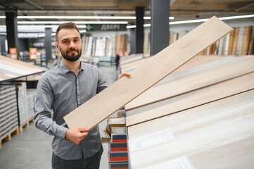 A male salesman-consultant in a hardware store sells laminate