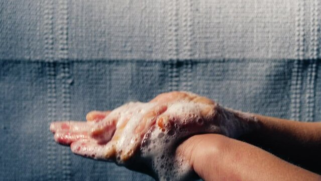 Woman washing hands with soapy suds and water