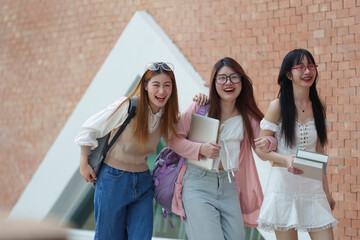 Three women are walking together, smiling and holding books. back to school