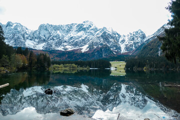 Panoramic view of Fusine Lake (Laghi di Fusine) and snow capped Julian mountain range in Tarvisio,...