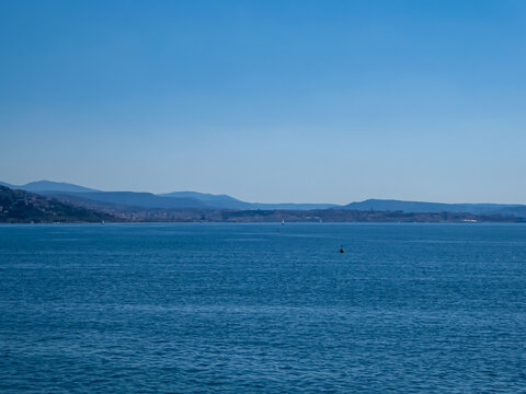 Scenic view of the coastline of the golf of Trieste in Friuli-Venezia Giulia, Italy, Europe. Blue sky in tranquil atmosphere at Adriatic Mediterranean sea in summer. Mountains and hills in background