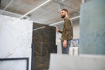 Confident male customer picking out wall tile materials for bathroom in hardware store