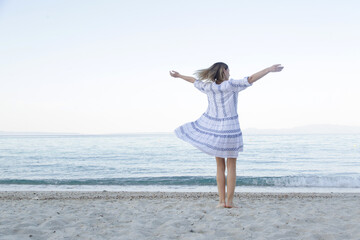Fototapeta na wymiar Middle aged woman in white blue dress enjoying at the empty sand beach