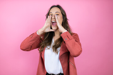 Young beautiful woman wearing casual jacket over isolated pink background shouting and screaming...
