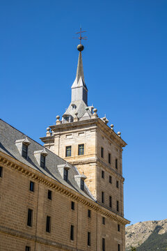 Photograph of the exterior tower of the monastery of El Escorial with the mountain in the background.