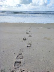 Shoe marks on the sand of a beach in Portugal near the ocean during the day.
