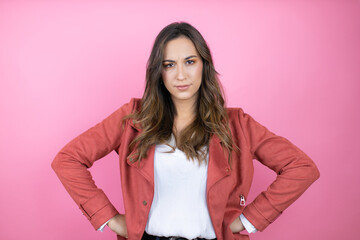 Young beautiful woman wearing casual jacket over isolated pink background skeptic and nervous, disapproving expression on face with arms in waist - obrazy, fototapety, plakaty