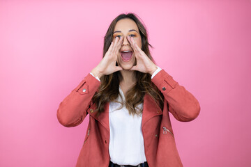 Young beautiful woman wearing casual jacket over isolated pink background shouting and screaming...