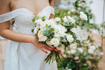 Bride in white wedding dress holding bouquet of white flowers