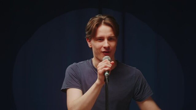 Stand Up cafe, comedy concert. Man entertainer presenting the artist on stage close-up. Presenter announcing comedian to audience using microphone, humorous monologue. Mentor coach training.