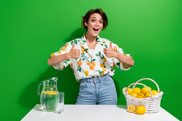 Photo of positive young lady brown bob hair thumbs up good job feedback first receipt lemon water juice isolated on green color background - obrazy, fototapety, plakaty