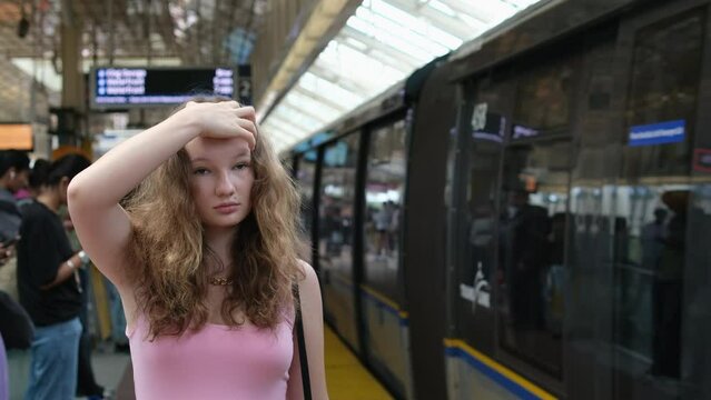 A girl is waiting for the skytrain in Vancouver, the train is approaching, the carriages are flying past, her hair is developing, her pink dress is a young Canadian