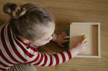 Enfant qui joue avec une boite permanence de l'objet Montessori