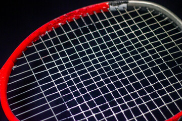 Red - gray racket with white strings on a black background