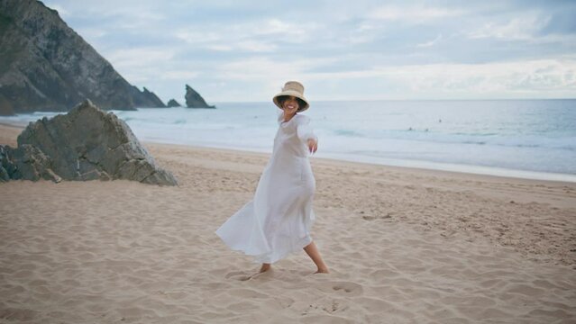 Joyful model dancing beach on cloudy day. Happy carefree woman enjoying summer