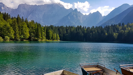 Colorful wooden boats on Fusine Lake (Laghi di Fusine) with scenic view of Mangart and Julian...