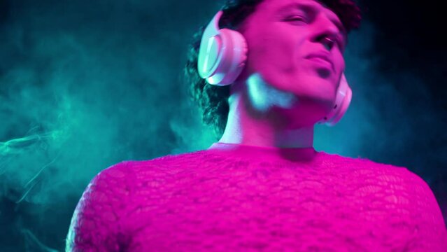 Hipster man dressed in net dancing in neon light in night club.Music, headphones