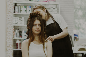Portrait of a young girl doing her hair at the hairdresser.