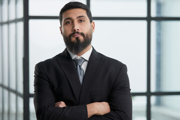 Confident young businessman standing, looking at camera.