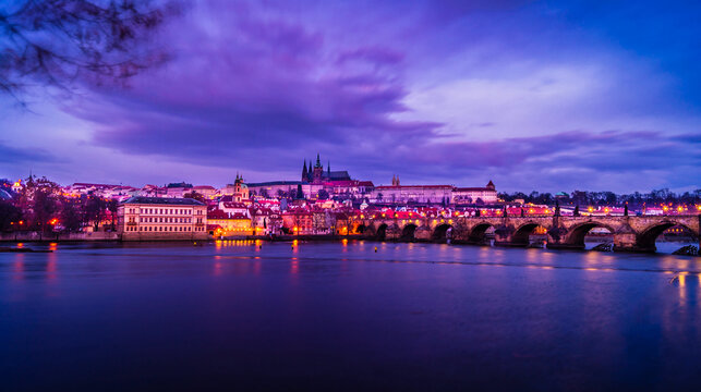 Twilight rosy evening sunset sky over the illuminated Prague Castle and Charles bridge seen towards the Lesser Quarter over the Vitava river in Prague, Czech Republic