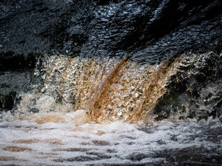 Closeup of fast running river water, White water flowing along the river bank. water splashes over rocks, flowing over rocks abstract background