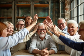 Group of senior people giving high five to each other and smiling while sitting in a cafe