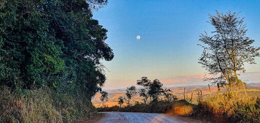 Sunset in the interior of Minas, landscape seen from the dirt road, flanked by green trees, a...