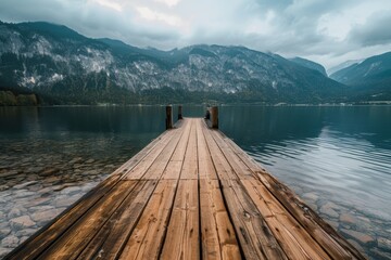   A wooden dock situated in a body of water, surrounded by towering mountains in the background and scattered clouds in the sky