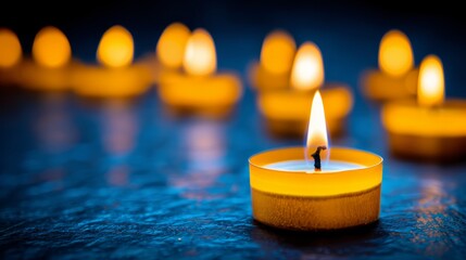   A tight shot of a solitary candle glowing on a table, surrounded by a line of other lit candles in the backdrop