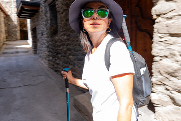 Woman doing rural tourism in a small mountain town as she passes by on her trekking day through the...