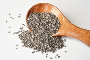 Close up of chia seeds in a wooden spoon on white background. Chia seeds contain fibre and omega-3...