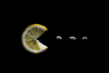Creative photography slice of lemon Pac Man shape eating lemon seeds, lemon in a shape of Pac-Man lemon with mouth Cut lemon and lemon seeds on textured black background