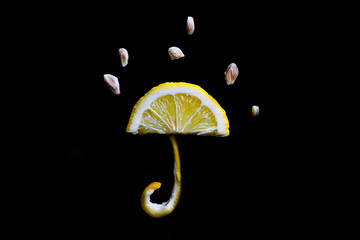 lemon in the shape of an umbrella and raindrops on a black background