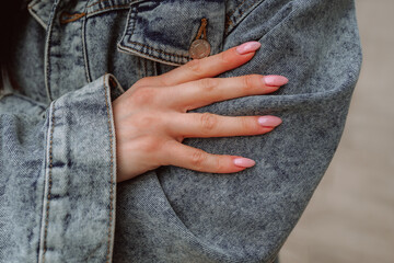 Fashion details of vintage denim jacket and female hands with pink manicure