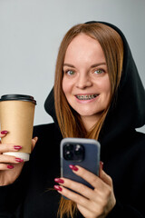 Caucasian young woman with braces on her teeth drinks coffee
