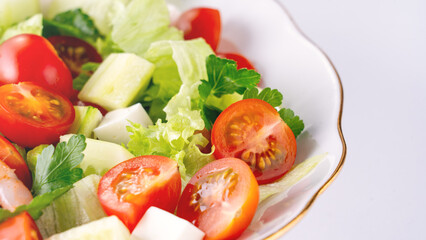 A close-up salad of fresh vegetables, a plate of fresh salad with vegetables and herbs. Greek salad with juicy tomatoes, feta cheese lettuce leaves green olives cucumber, fresh parsley. Homemade food.