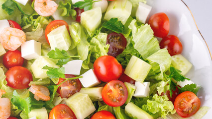 A close-up salad of fresh vegetables, a plate of fresh salad with vegetables and herbs. Greek salad with juicy tomatoes, feta cheese lettuce leaves green olives cucumber, fresh parsley. Homemade food.