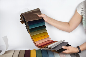 A woman is holding a catalog with fabric samples in her hands, a woman is choosing a fabric for her...