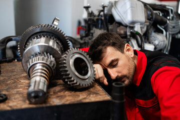 Tired mechanic sleeping at work inside workshop.