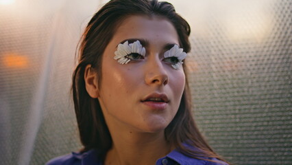 Closeup woman eyelashes blossoms at blurred backdrop. Makeup with flower petals
