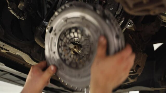 Mechanic installs new clutch disc in car. Automotive repair workshop scene, hands replace worn components. Vehicle maintenance, clutch assembly, gearbox service. DIY auto workshop instruction.