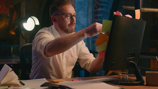 Caucasian business man at night office evening overtime overworked deadline businessman male worker guy throw sticky notes many lot of tasks on computer monitor holding head stress overload burnout