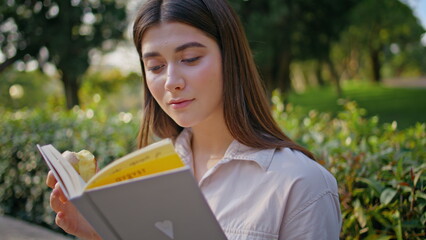 Beautiful lady reading romance in serene green park closeup. Thoughtful reader