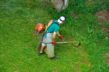 Gardener cutting overgrown grass in spring