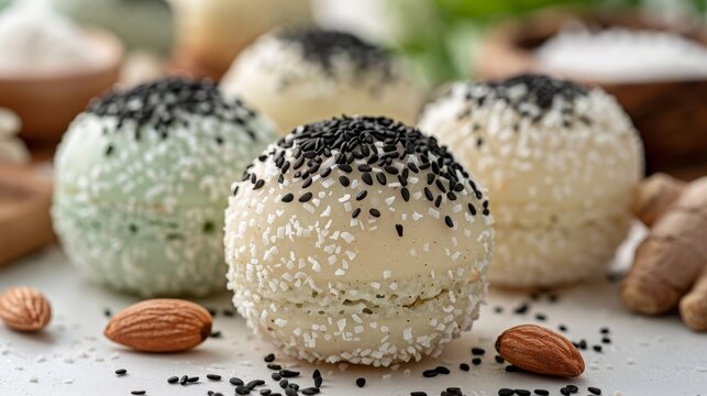   A white table is laden with various desserts, their surfaces adorned with contrasting black and white sprinkles and almonds