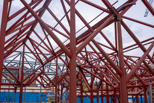 Complex network of red beams forming a light and geometric structure similar to an artificial spider web at the construction site of a building