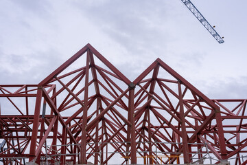 Geometric composition of red metal beams and a blue crane in a modern construction against a clear...