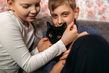 Obraz premium Boy and Girl Holding Black Cat
