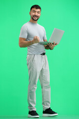 A man, full-length, on a green background, with a laptop